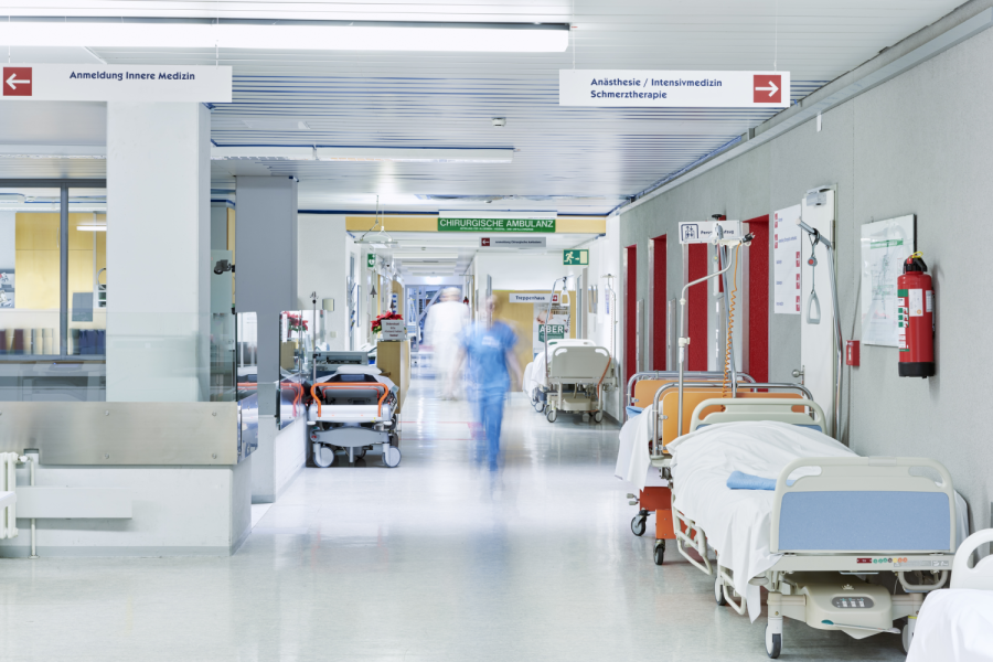 Flur im Krankenhaus mit unscharfem Arzt in Bewegung und Lift rot und Bett Bild: upixa/stock.adobe.com